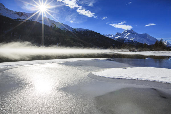 Winter sun light up the frozen Lake Silvaplana surrounded by mist Maloja Canton of Graubünden Engadine Switzerland Europe