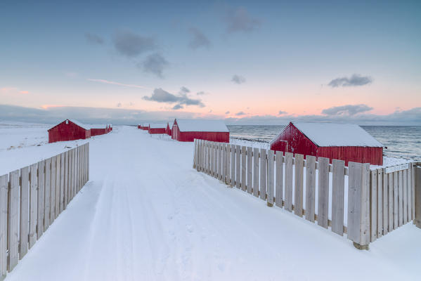 Pink light and snow surround the typical fishermen houses called Rorbu at Eggum Vestvagøy Island Lofoten Islands Norway Europe