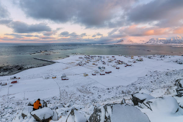 Photographer in action admires the fishing village under a colorful sky Eggum Vestvagøy Island Lofoten Islands Norway Europe