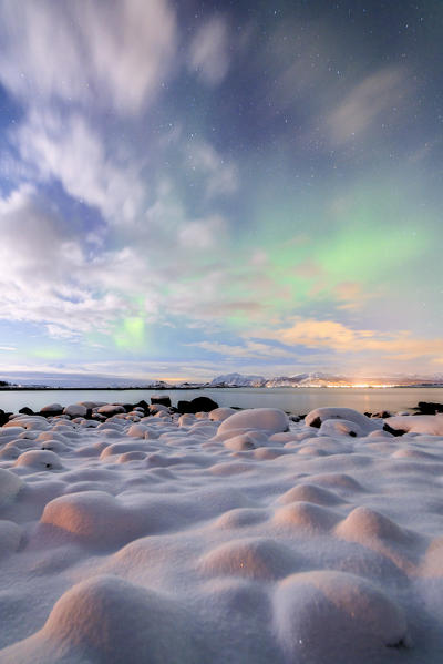 The pink light and the aurora borealis illuminate the snowy landscape on a starry night Strønstad Lofoten Islands Norway Europe