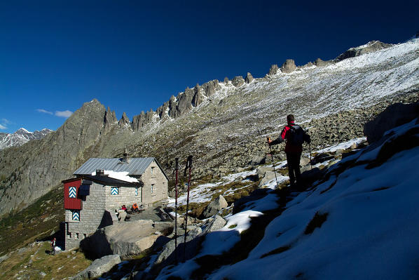 Hiker proceeds near a refuge at Sciora, Bondasca Valley Rhaetian Alps Switzerland Europe