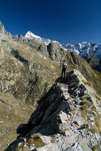 Hiker overlooking towards the Mount Disgrazia by a walking section of the trail Rome. Valmasino. Valtellina. Lombardy Italy Europe