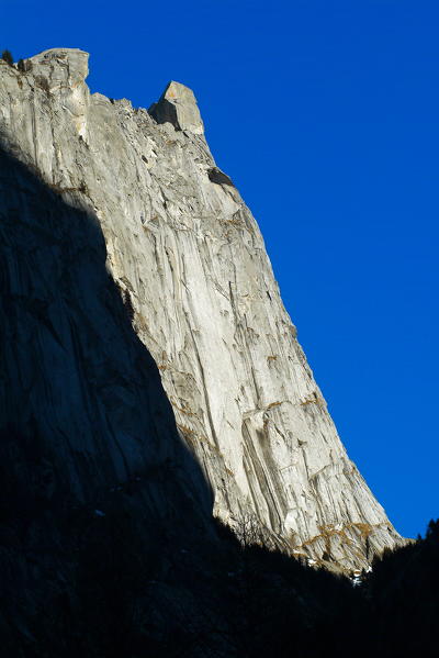 The impressive wall of smooth granite of Qualido illuminated by the sun during a summer day. Mello Valley. Valmasino. Valtellina. Lombardy Italy Europe