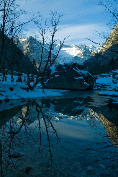 The snowy peaks of Merdarola Valley are reflected in the icy waters of the Countess Bidet famous puddle colored turquoise. Valmasino. Valtellina. Lombardy Italy Europe