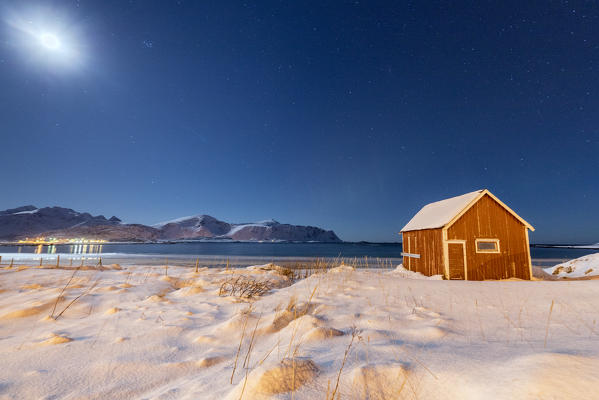 Moonlight on a typical fishermen cabin surrounded by snow Ramberg Flakstad Nordland County Lofoten Norway Europe