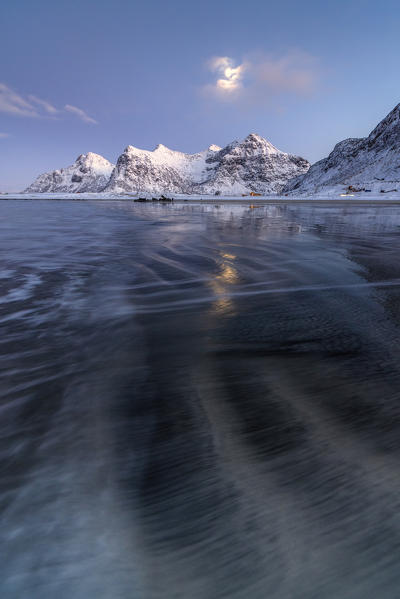 Full Moon reflected in the icy sea  around the surreal Skagsanden beach Flakstad Nordland county Lofoten Islands Norway Europe