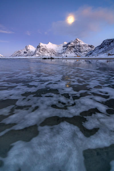 Full Moon reflected in the icy sea  around the surreal Skagsanden beach Flakstad Nordland county Lofoten Islands Norway Europe