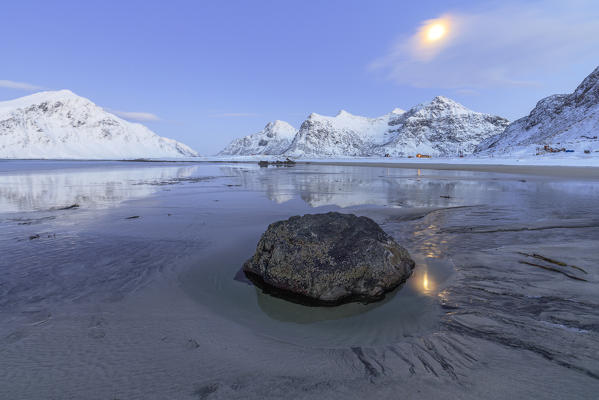 Full Moon reflected in the icy sea  around the surreal Skagsanden beach Flakstad Nordland county Lofoten Islands Norway Europe