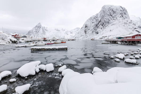 Icy sea and snowy peaks around the typical houses called rorbu and fishing boats Hamnøy Lofoten Islands Northern Norway Europe