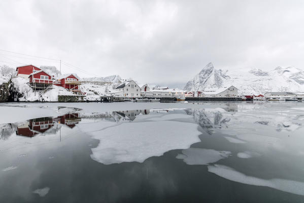 Icy sea and snowy peaks around the typical houses called rorbu and fishing boats Hamnøy Lofoten Islands Northern Norway Europe