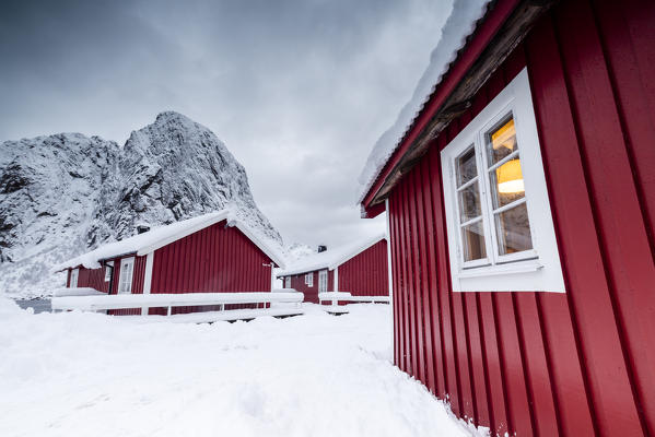 Clouds on the typical red houses of fishermen called Rorbu surrounded by snowy Hamnøy Lofoten Islands Northern Norway Europe