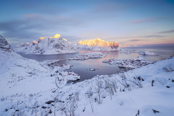 The pink colors of dawn frame the fishing villages and the frozen sea Reine Nordland Lofoten Islands Norway Europe