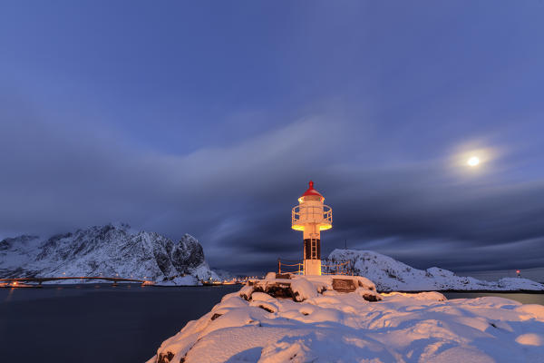 Lighthouse and full moon in the Arctic night with the village of Reine in the background Nordland Lofoten Islands Norway Europe