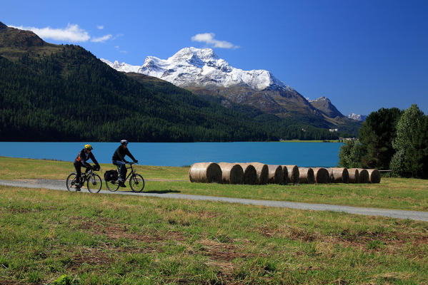 Tourists on mountain-bike enjoying the peace around the lake of Sils in high Engadine, in the background Piz De La Margna Engadine Switzerland Europe