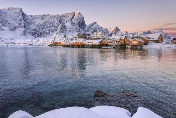 The colors of dawn frames the fishermen houses surrounded by snowy peaks Sakrisøy Reine Nordland Lofoten Islands Norway Europe