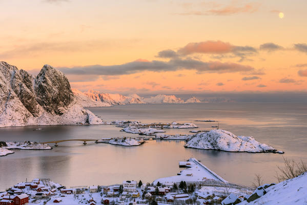 The pink colors of sunset and snowy peaks surround the fishing villages Reine Nordland Lofoten Islands Norway Europe