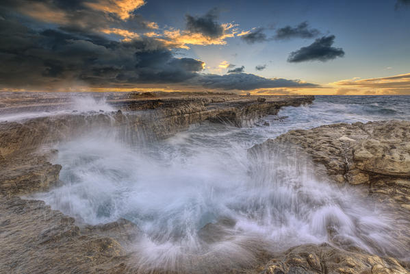 Sunset on the cliffs of Devil's Bridge submerged by crashing waves Caribbean Antigua and Barbuda Leeward Islands West Indies