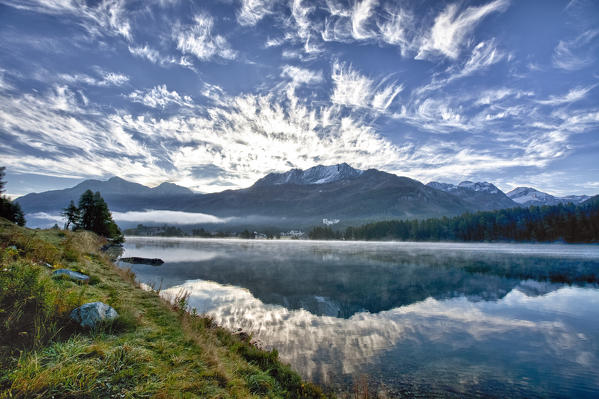 Piz Corvatsch reflected in the lake of Sils in the morning and some unuzual clouds in the sky. Engadine Switzerland Europe