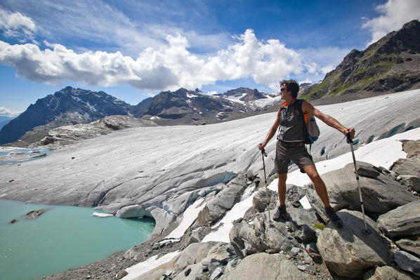 After a long hike along the path Luigi Marson from Bignami Hut, a hiker has reached the the glacier Fellaria and its epiglacia lake,  Valmalenco, Valtellina, Lombardy Italy Europe