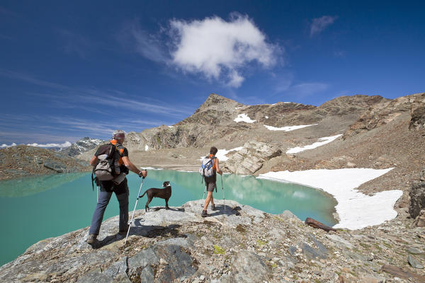 Hikers near the little lake under Cima Fontana in Valmalenco, Lombardy Italy. Europe