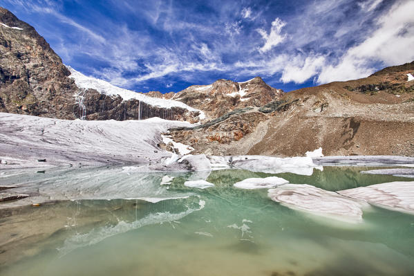 A lake created by the summer heat near the Fellaria glacier in Valmalenco and some particular clouds in the sky, Malenco Valley Lombardy Italy Europe