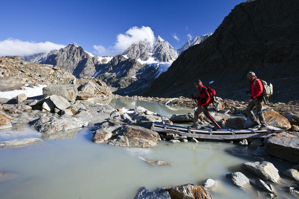 Hikers walking along the Valmalenco High Route, Alta Via della Valmalenco, which, thanks to its variety of places, is one of the most beautiful high altitude excursion routes in the Alps, that extends for over 110 km - Valmalenco, Valtellina, Lombardy Italy Europe