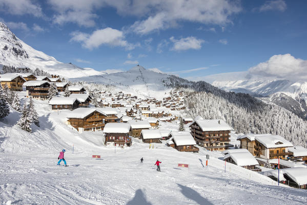 Skiers on the ski slopes frame the typical alpine village Bettmeralp district of Raron canton of Valais Switzerland Europe