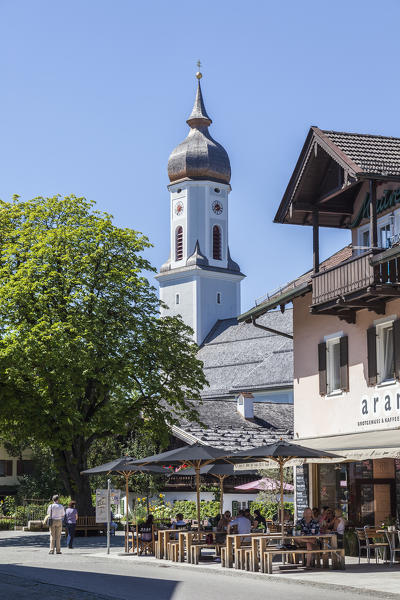 The typical bell tower and hotels surrounded by peaks and woods Garmisch Partenkirchen Oberbayern region Bavaria Germany Europe