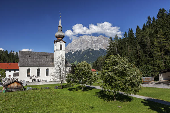 Typical church of alpine village surrounded by peaks and woods Garmisch Partenkirchen Oberbayern region Bavaria Germany Europe