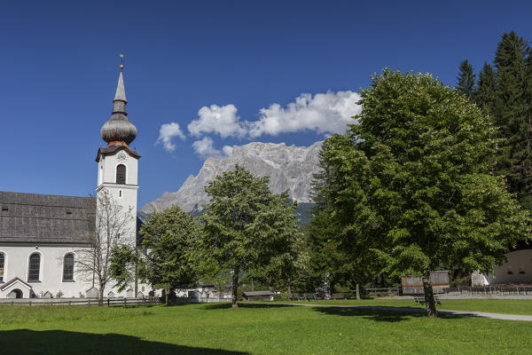 Typical church of alpine village surrounded by peaks and woods Garmisch Partenkirchen Oberbayern region Bavaria Germany Europe