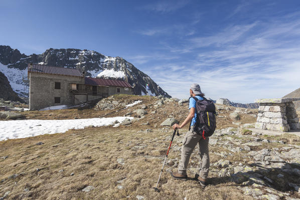 Hiker towards Rifugio Tonolini framed by high peaks Val Malga Adamello Regional Park province of Brescia Lombardy Italy Europe