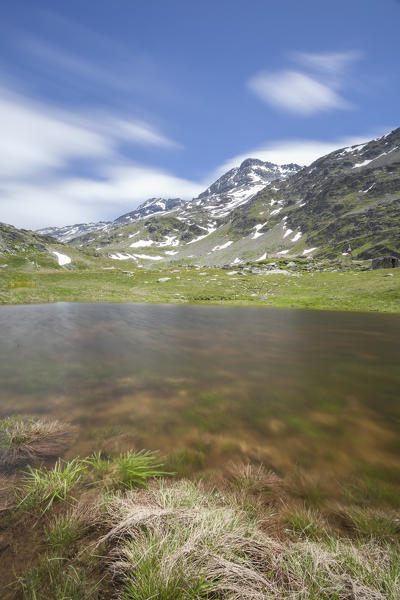 Lake Emet surrounded by green meadows and peaks Montespluga Chiavenna Valley Sondrio province Valtellina Lombardy Italy Europe