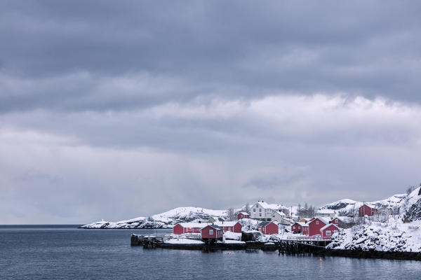 Cold sea and snowy peaks frame the fishing village at dusk Nusfjord Nordland Lofoten Islands Northern Norway Europe