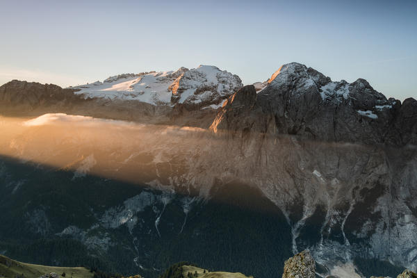 The orange light beam frames the snowy peaks of Marmolada at dawn Cima Belvedere Val di Fassa Trentino Alto Adige Italy Europe