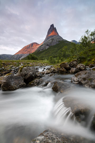 Waterfall frames the Stetinden mountain peak illuminated by midnight sun Tysfjord Norway Europe