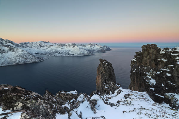 View of the Mefjorden framed by frozen sea and pink sky at sunrise from the top of Mount Hesten Senja Tromsø Norway Europe