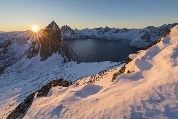 First lights of sunrise on Mount Segla and Mefjorden framed by the frozen sea seen from peak Hesten Senja Tromso Norway Europe