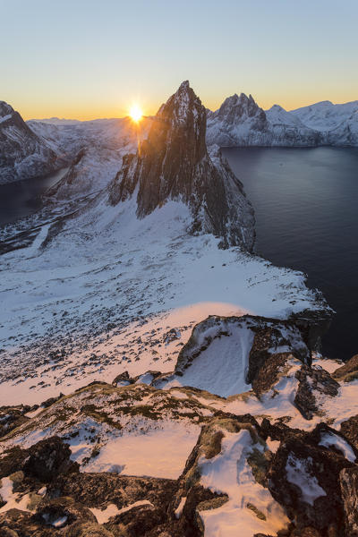 First lights of sunrise on Mount Segla and Mefjorden framed by the frozen sea seen from peak Hesten Senja Tromso Norway Europe