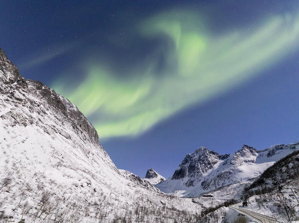 Panorama of  Northern lights and stars on the snowy peaks along the  National Tourist Route Bergsbotn Senja Tromsø Norway Europe