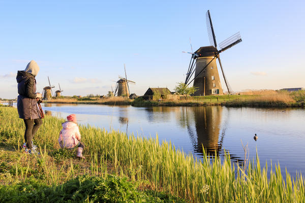 Mother and child admire the typical windmills reflected in the canal Kinderdijk Molenwaard South Holland The Netherlands Europe