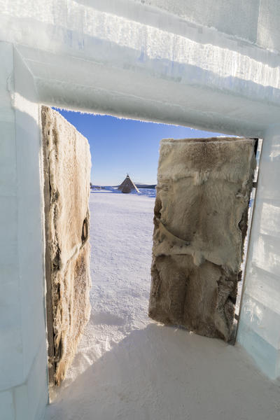 Sami tent in the snow seen from the open doors of a room, Ice Hotel, Jukkasjarvi, Kiruna, Norrbotten County, Lapland, Sweden