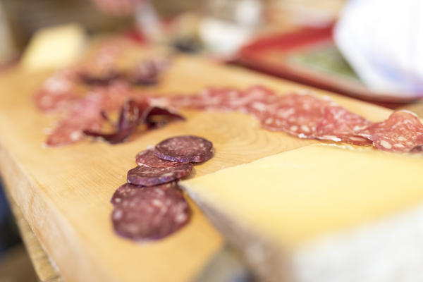 Local salami on wooden chopping board, San Romerio Alp, Brusio, Canton of Graubünden, Poschiavo valley, Switzerland