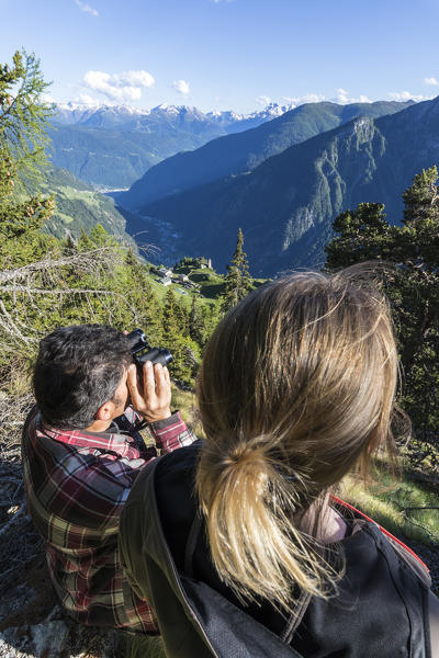 Hikers on Sentiero del Carbonaio with binoculars, San Romerio Alp, Brusio, Canton of Graubünden, Poschiavo valley, Switzerland