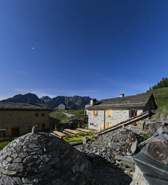 Panoramic of mountain retreat under starry sky, San Romerio Alp, Brusio, Canton of Graubünden, Poschiavo valley, Switzerland