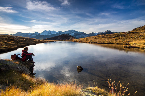 A hiker enjoying the first daylights in front of the landscape of Adamello-Presanella - Tonale mount, Lombardy, Italy. Europe 