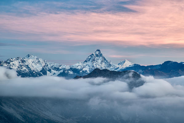 The unmistakable Matterhorn shape colored by the first lights of the sunrise from a peak in the Mont Avic Natural Park - Aosta Valley, Italy Europe