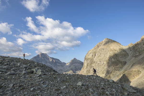 Hikers on rocks with Piz Polatschin on the background, Lej Lagrev, Silvaplana, canton of Graubünden, Engadine, Switzerland