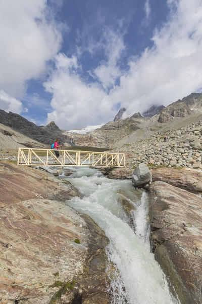 Hiker on walkway of the path Sentiero Glaciologico of Fellaria Glacier, Malenco Valley, Valtellina, Lombardy, Italy