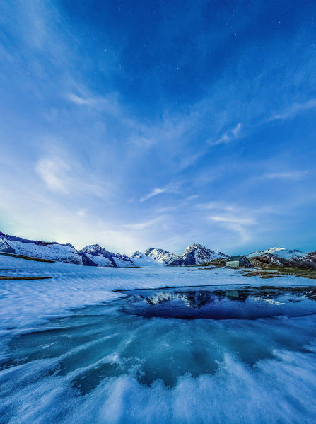 A vertical panoramic shot of the thawing of Lake Scermendone in the blue lights of dusk. Scermendone Alp. Sondrio. Valtellina. Lombardy. Italy. Europe