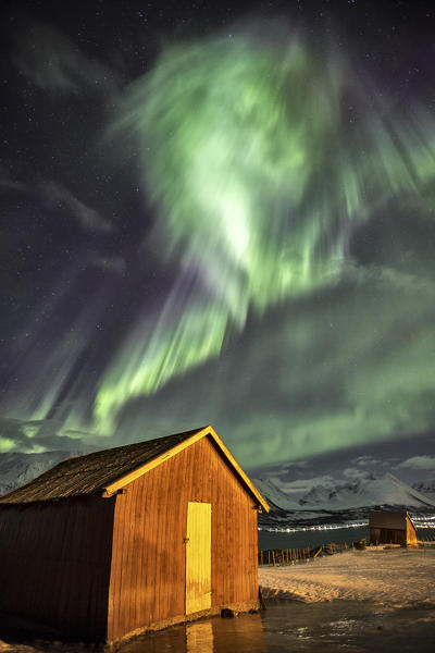 Northern Lights illuminates the wooden cabin at Lenangsoyra Lyngen Alps Tromsø Lapland Norway Europe